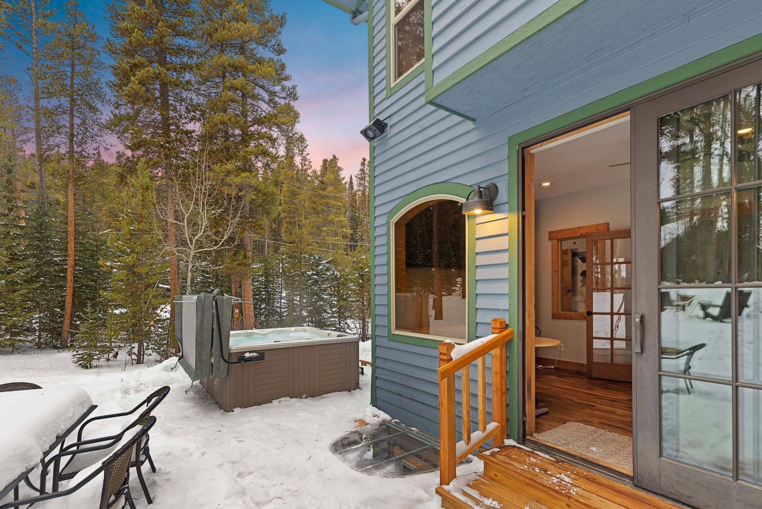 Steaming private hot tub in the snowy backyard of Lodestone Retreat, next to the lower-level patio door
